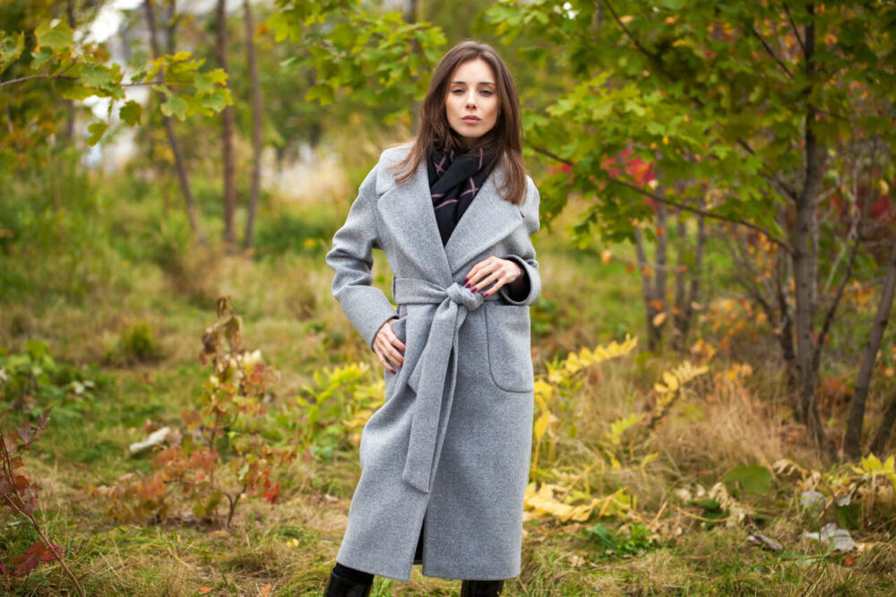 Schöne Frau im grauen Damenmantel in der Natur